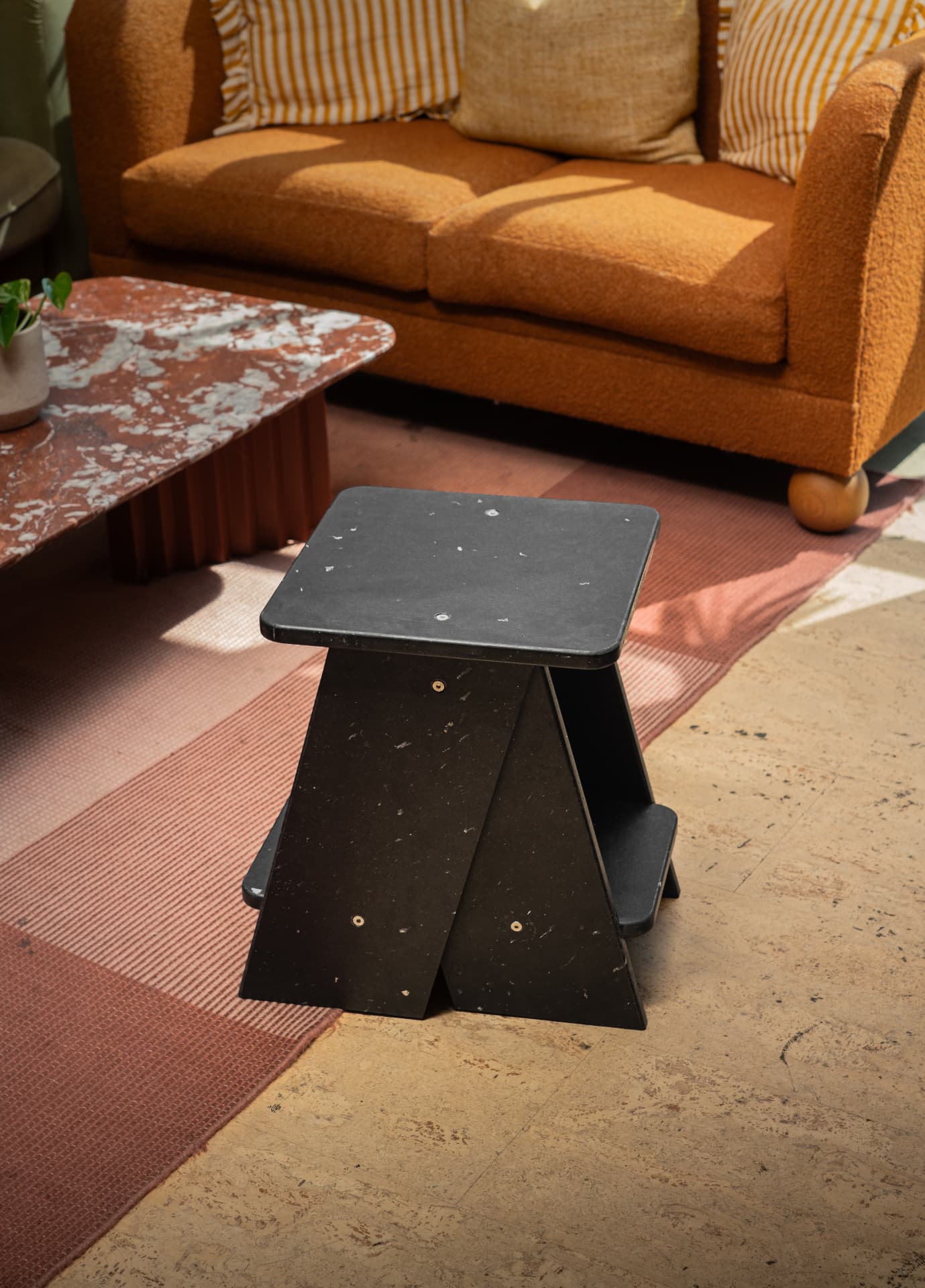 MadeBy speckled black step stool used as a side table in a living room