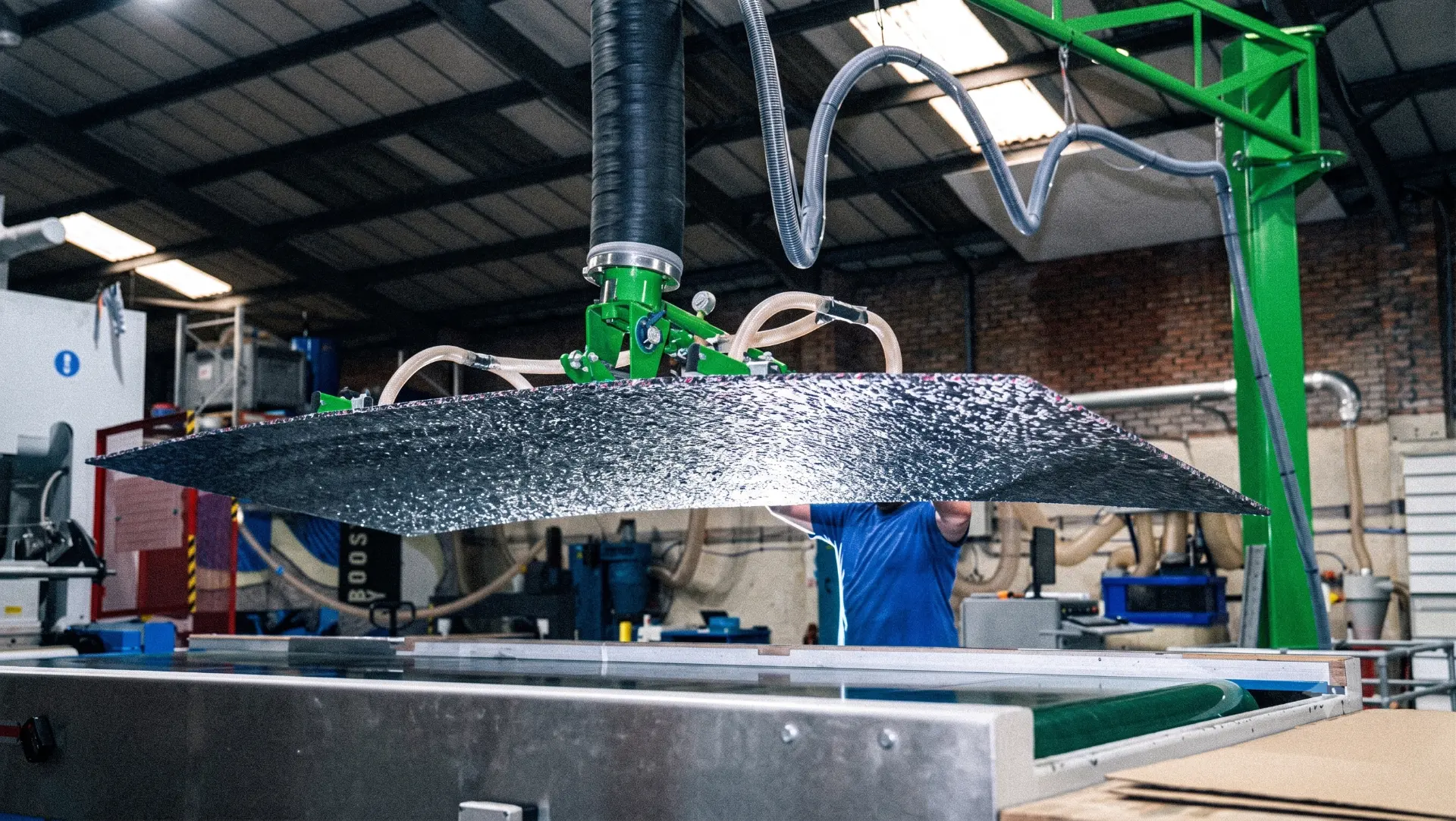 Sheet of recovered material held by a vacuum lifter above a processing bed