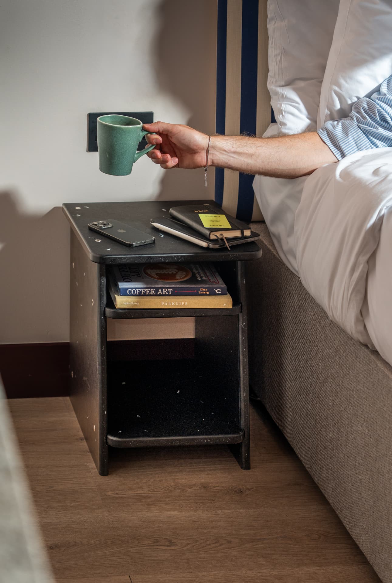 MadeBy recovered-material bedside table in use beside a hotel bed